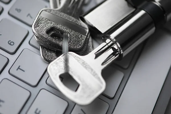 Silberner Schlüssel mit Schloss liegen auf weißem Tastatur-Nahaufnahme-Hintergrund. lizenzfreie Stockfotos