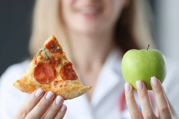 Dottore in possesso di un pezzo di pizza e mela verde nelle sue mani primo piano — Foto Stock