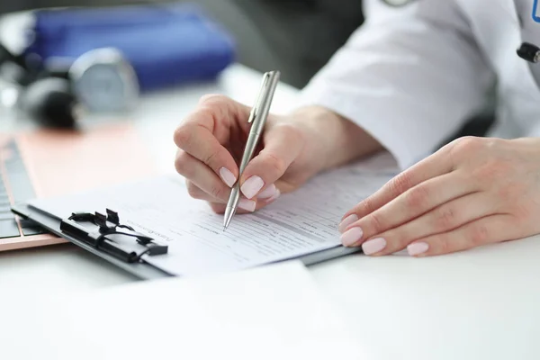 Medico che compila la cartella clinica dei pazienti in ufficio primo piano Fotografia Stock