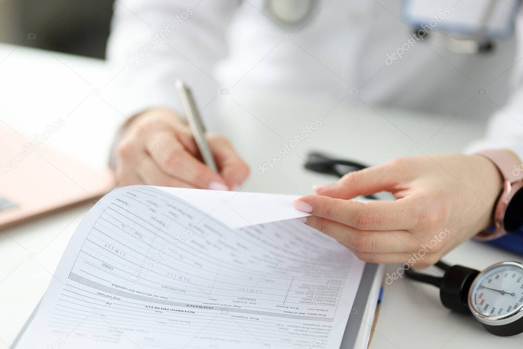 Doctor writing with ballpoint pen in patients medical history closeup