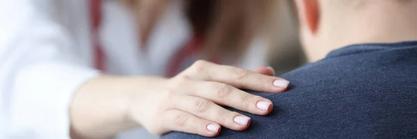 Ärztin hält Schulter eines männlichen Patienten in Nahaufnahme Stockfoto