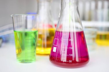 Kimya laboratuarı masasında kırmızı sıvıyla test tüpü yakın plan.