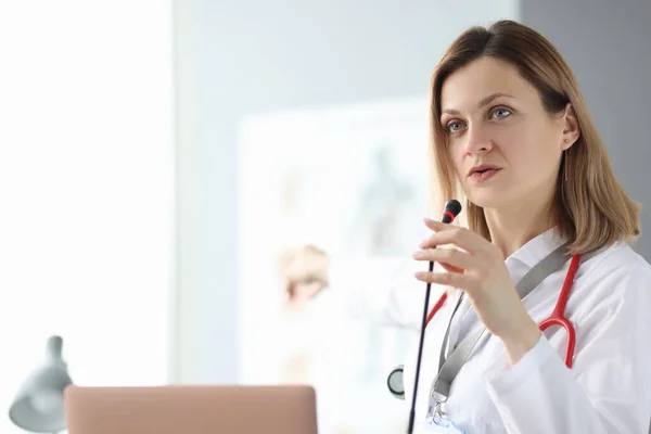Eğitim seminerinde mikrofona konuşan doktor.