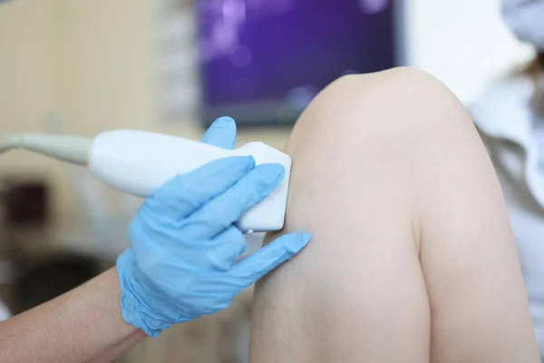 Arzt macht Ultraschalluntersuchung des Kniegelenks des Patienten lizenzfreie Stockfotos