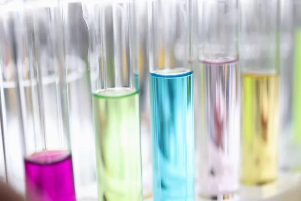 Glazen reageerbuizen met veelkleurige vloeistoffen op tafel in chemisch laboratorium close-up Stockfoto