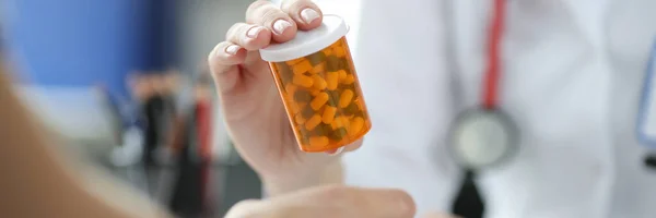 Médecin tenant un bocal de médicaments devant le patient gros plan — Photo