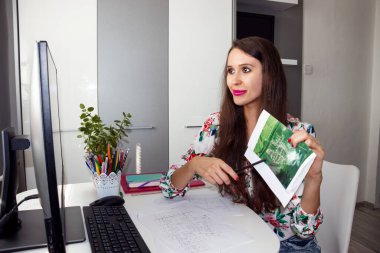 Gülümseyen, mutlu bir kadın, mimar, iç mimar binanın yeniden inşası ve yenilenmesi üzerinde çalışıyor. Haritaları ve planları müşteriye sunuyor. Video Çağrısı Uzaktan Yapılıyor