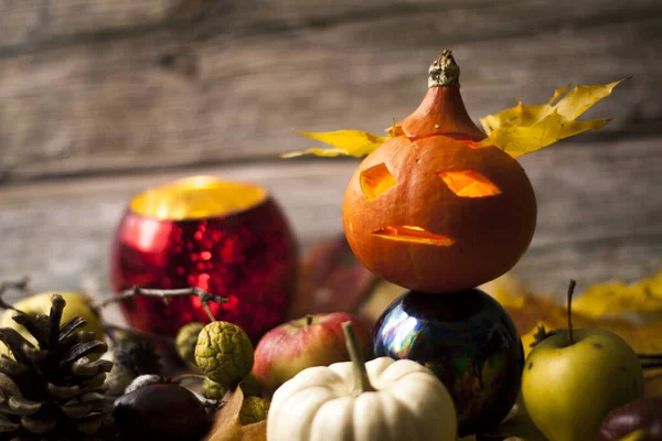 Bodegón de Halloween con calabaza con orejas hechas de hojas de arce, manzanas, vela, cono sobre fondo de madera. —  Fotos de Stock
