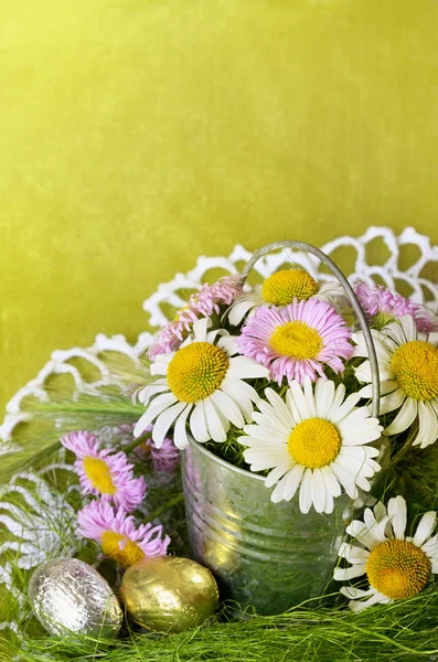 Bouquet of daisies in a metal bucket and shocolate eggs — Stock Photo, Image
