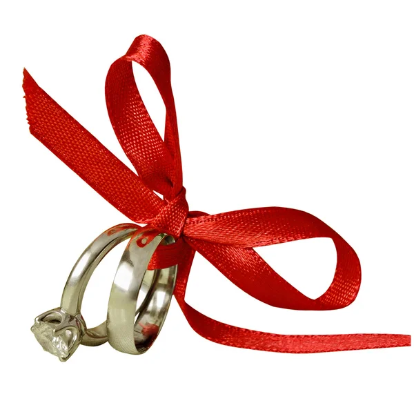 Engagement and wedding rings tied with red ribbon — Stock Photo, Image