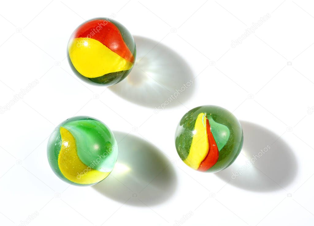 three colorful glass marbles to play on white background