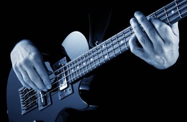 Sahnede elektro gitar çalan basçının elleri, mavi görüntü.