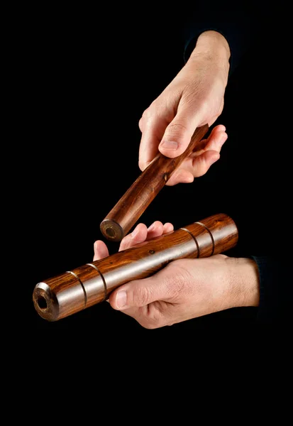 hands playing cuban clave percussion instrument on black background