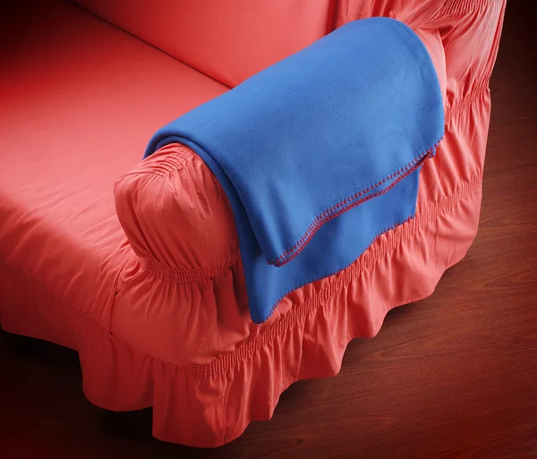 Blaue Decke auf rotem Sofa Arm — Stockfoto