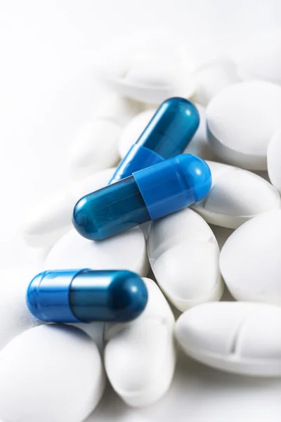 Blaue Pillen und weiße Tabletten — Stockfoto