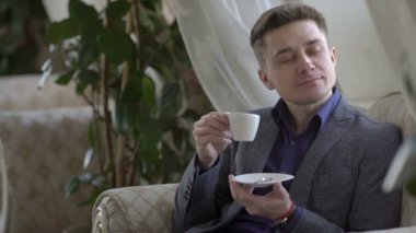 Genç adam kahve içiyor.