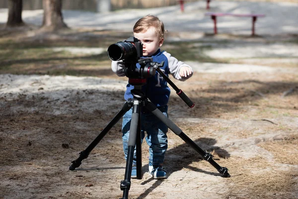 Young photographer child taking photos with camera on a tripod — Stock Photo, Image