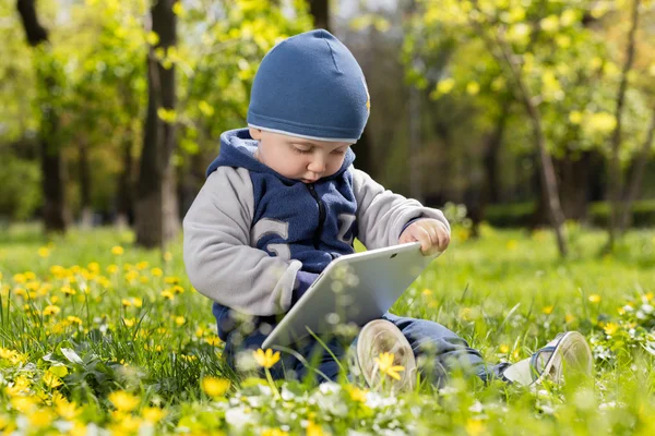 Criança brincando com tablet no parque . — Fotografia de Stock