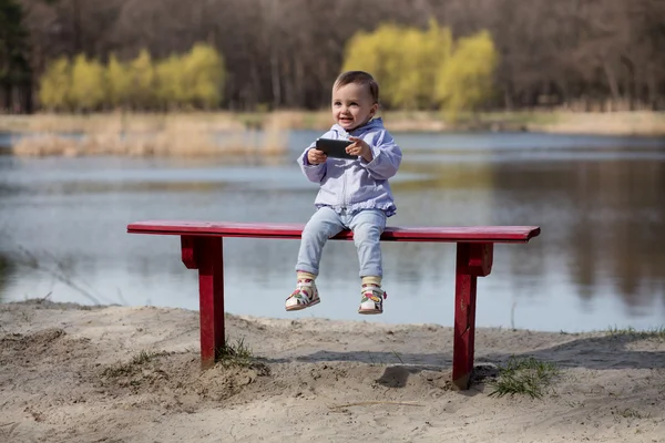 Child playing with smartphone in the park. — Stock Photo, Image