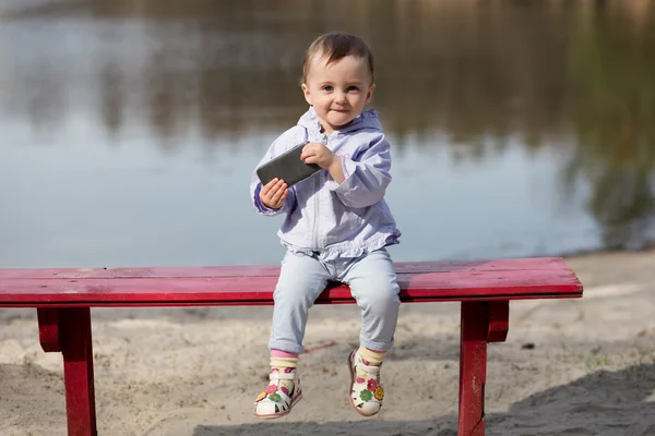 Ребенок играет со смартфоном в парке . — стоковое фото