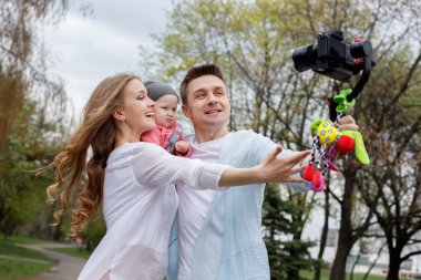 Happy young family taking video selfies with her camera on the gimbal steadycam clipart