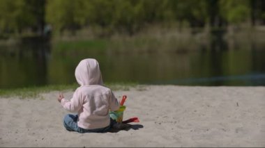 Mutlu çocuk yazın kumsalda kumla oynuyor.