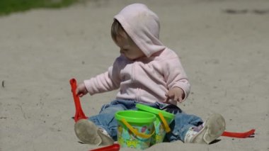 Mutlu çocuk yazın kumsalda kumla oynuyor.