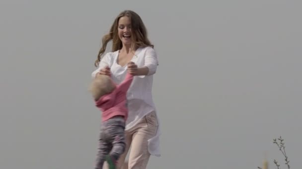 Mãe alegre girando torção fazendo círculo com sua filha pequena — Vídeo de Stock