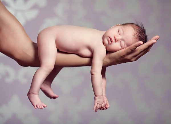 Small child sleeps on the hands of parents