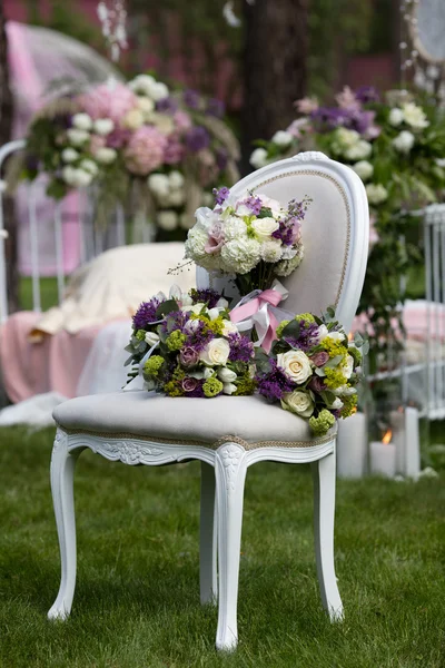新娘在森林里的老式椅子上设置的花束 免版税图库照片