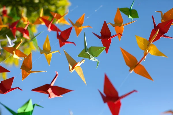 Renkli origami kuşlar uçuyor. Gökyüzü arka plan.