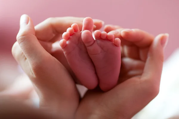 Baby fötter kupade i mödrar händer — Stockfoto