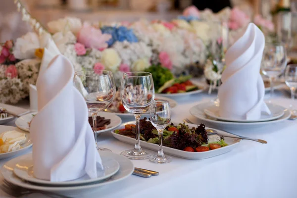 Geserveerd voor een bankettafel. Wijnglazen met servetten, glazen en salades. — Stockfoto