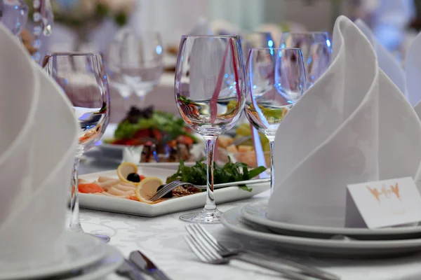 Wijnglazen, servetten en salade op de tabel voor de feestzaal. — Stockfoto