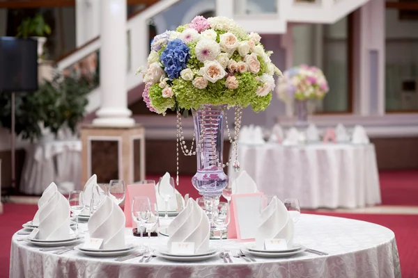 Bloemen, wijn glazen, servetten en salade op de tabel voor de feestzaal. — Stockfoto