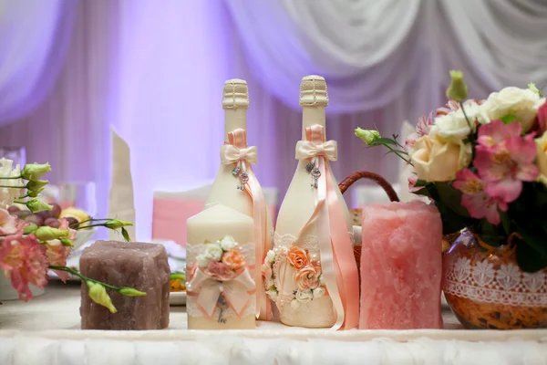 Garrafas de champanhe decoradas, velas e flores na mesa de casamento com decorações em restaurante . — Fotografia de Stock