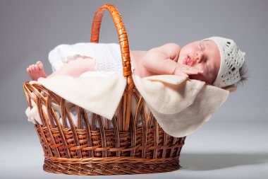 Yeni doğan bebek sepet içinde onun karnına uyuyor