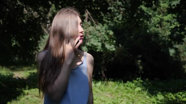 Ritratto giovane bella donna in un abito estivo nella foresta è seduta su un ceppo, si è persa e chiama il servizio di soccorso per trovarla — Video Stock