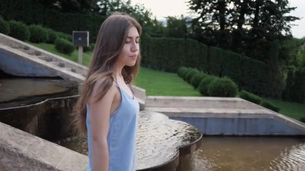 Porträt der jungen hübschen Touristenmädchen in Kleid, sie geht schöne Treppen mit Wasserfällen hinunter. Zeitlupe — Stockvideo