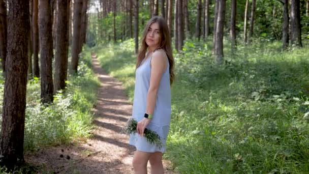 Hermosa joven romántica mujer en parque o bosque pasea flores. Tiene margaritas ramo de flores silvestres. Movimiento lento — Vídeos de Stock