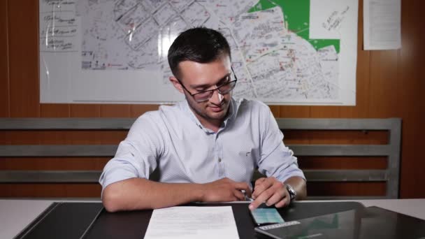 Un homme confiant caucasien positif utilisant un téléphone portable dans une application mobile alors qu'il était assis à table — Video