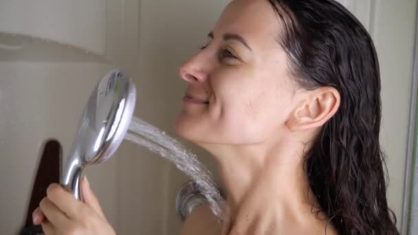 Een jong meisje giet koud water uit de douche close-up. concept van driftbuien. Versterking van de immuniteit — Stockvideo