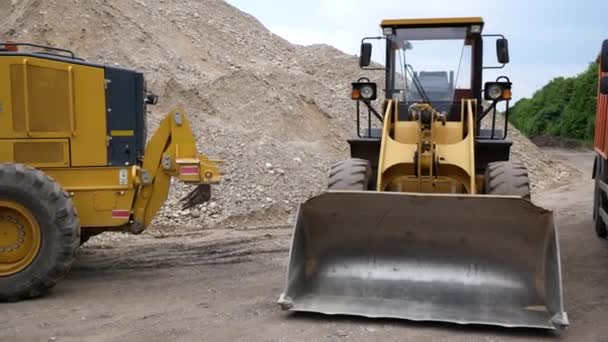 Große Baumaschinen sind auf der Baustelle. Lader, Straßenhobel, Kipper. Vor dem Hintergrund riesiger Trümmerberge — Stockvideo