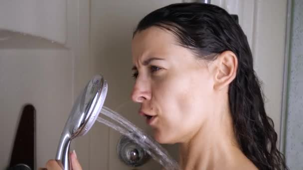Zabawna dziewczyna stojąca w wannie trzyma prysznic śpiewając piosenki pod prysznicem. Kąpiel młodej kobiety. Zwolniony ruch — Wideo stockowe