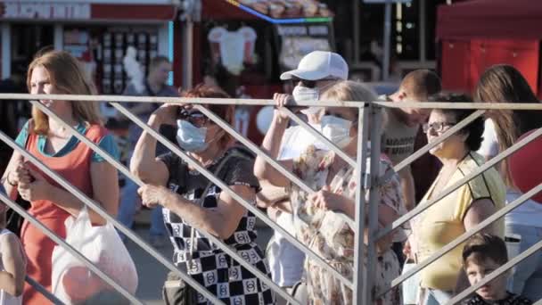 Foule de gens se tiennent derrière la clôture portant des masques médicaux de protection contre le virus lors d'un événement de masse. concept de violation du régime du masque, distanciation sociale. Russie, Stavropol - 29.08.20 — Video