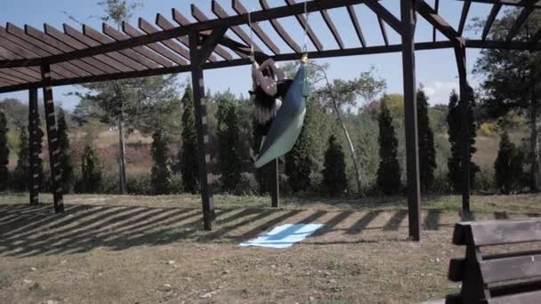 Jovem praticando ioga aérea no parque. Este tipo de ioga em telas de tecido especiais. Homem praticando ioga voar em redes. Movimento super lento — Vídeo de Stock