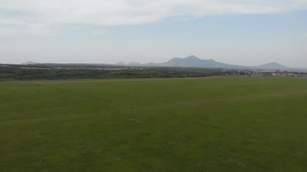 在机场草地跑道上方的空中飞行，为轻型飞机在农田之间的景观。山区小机场 — 图库视频影像