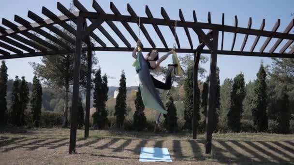 Jonge vrouw beoefent anti-zwaartekracht yoga op hangmat in Park. Meisje is bezig met vliegen, luchtyoga zomer in de natuur — Stockvideo