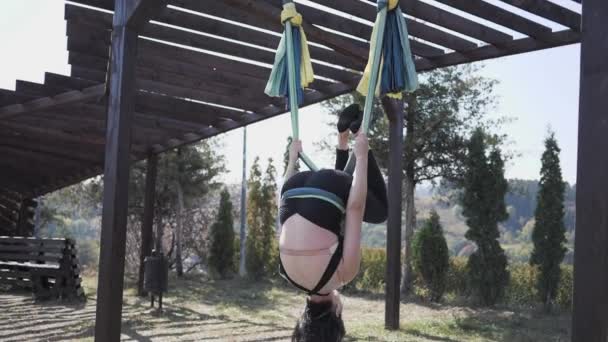 Giovane donna pratica fly yoga su amaca a Park. Yoga aereo antigravità nel parco cittadino nella natura estiva — Video Stock