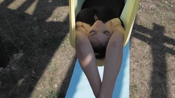 Ung kvinna vilar i en hängmatta i parken. Långsamma rörelser — Stockvideo